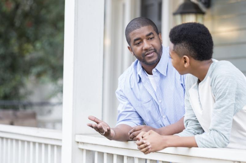 一位父亲靠在前廊的栏杆上，和他不到十岁的儿子认真地交谈着.